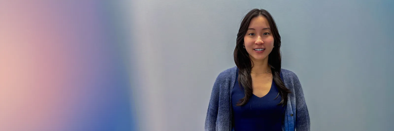 Alexa Siu standing in front of a colorful gradient background.