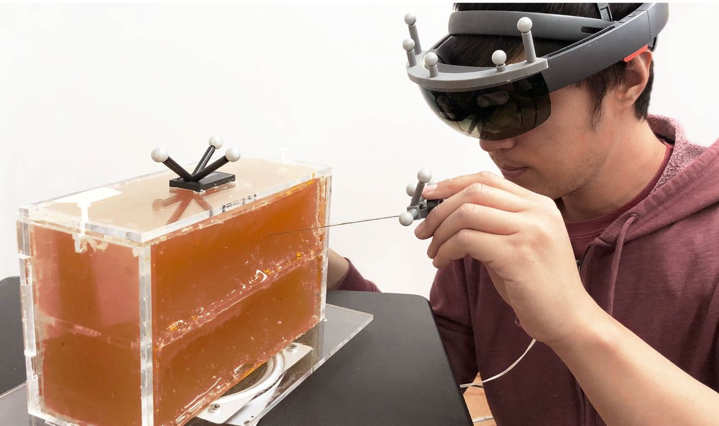A user wearing a HoloLens inserting a needle into phantom tissue.